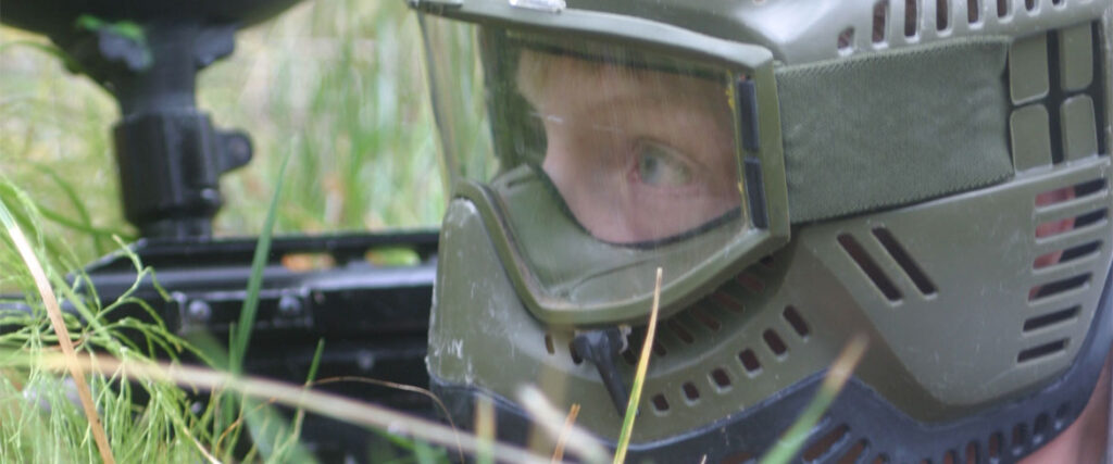 Paintballspelare i ansiktsmask i gräset